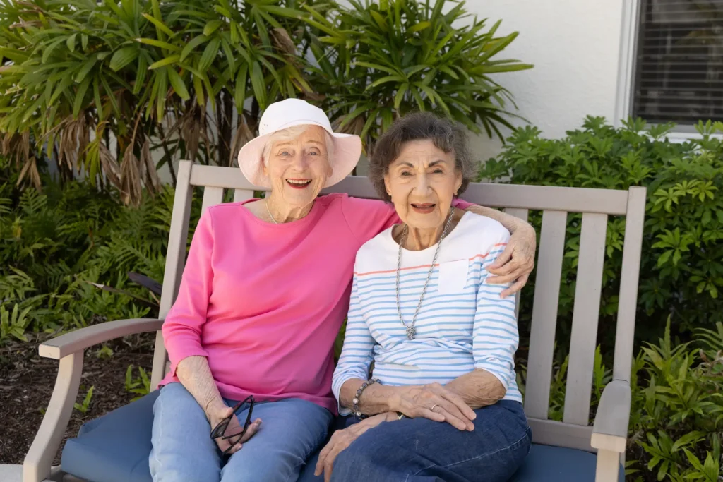 Two senior women hugging that met at Amavida, showing senior companionship in Fort Myers, FL.