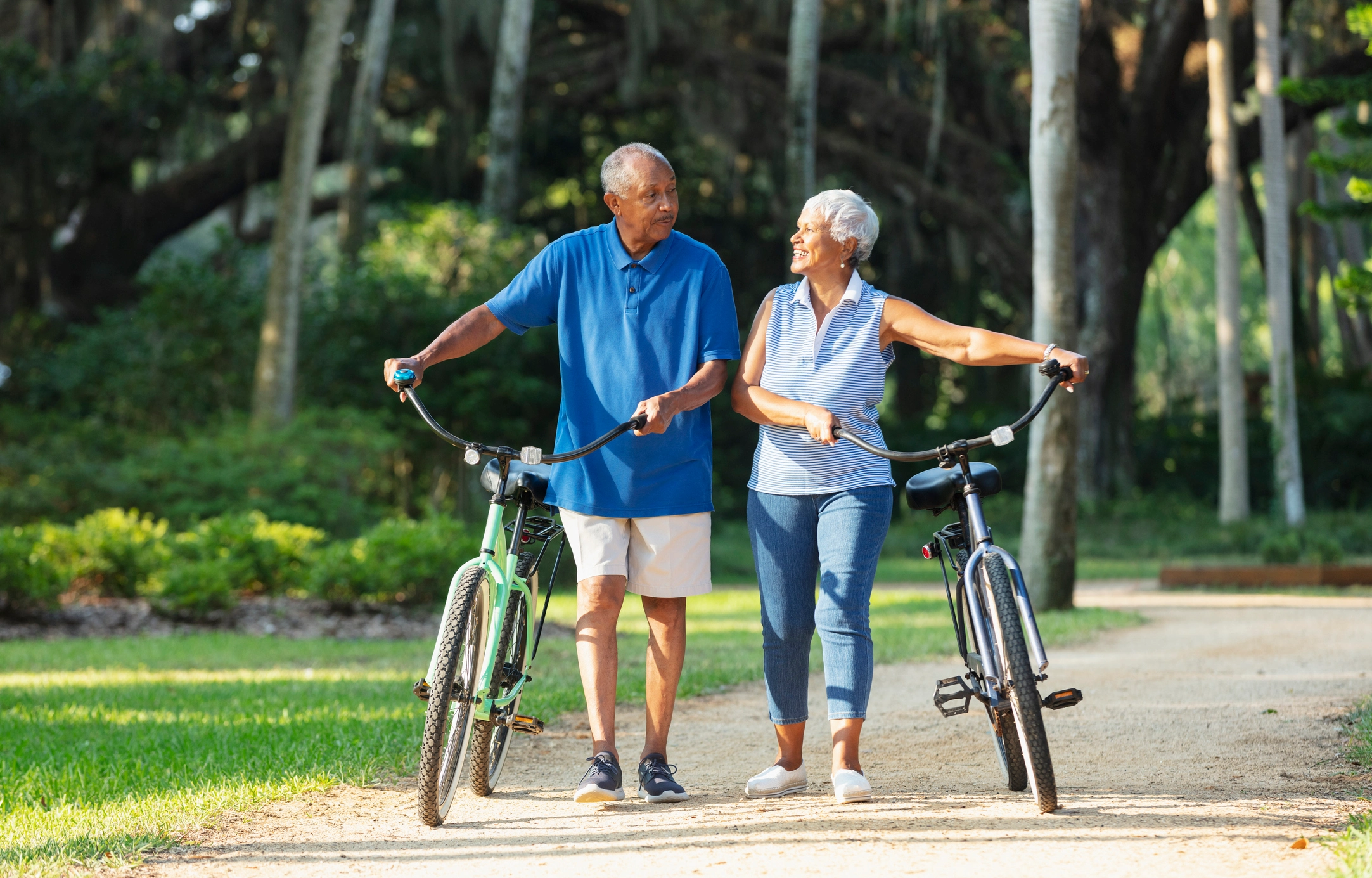An elderly couple walking while holding their bikes and and talking about 10 Ways Independent Living Boosts Your Health in Retirement.